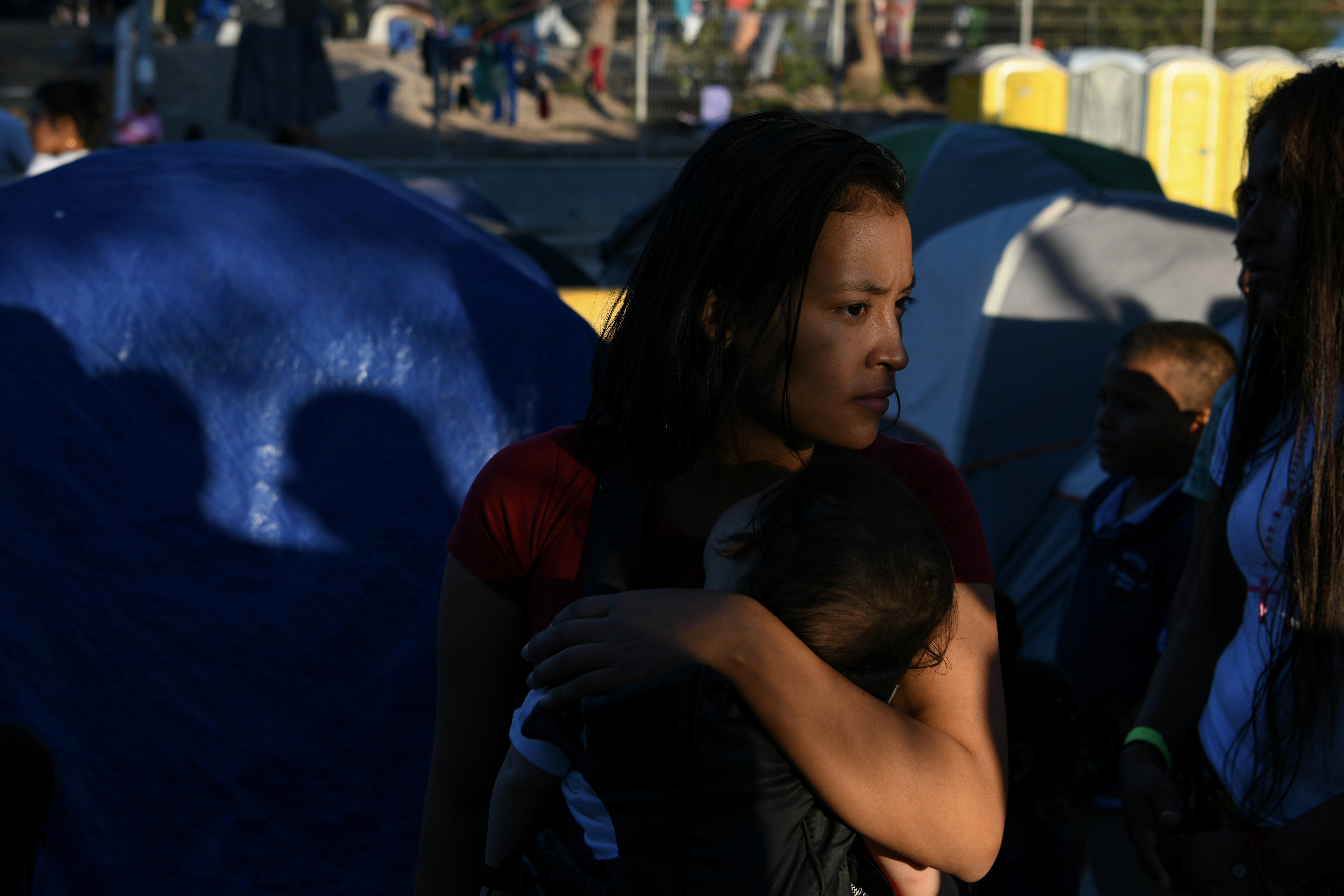 A Honduran migrant mother and child wait in line for a dinner provided by volunteers at a makeshift encampment occupied by asylum seekers sent back to Mexico from the US in Matamoros, Tamaulipas, Mexico, October 27, 2019.  