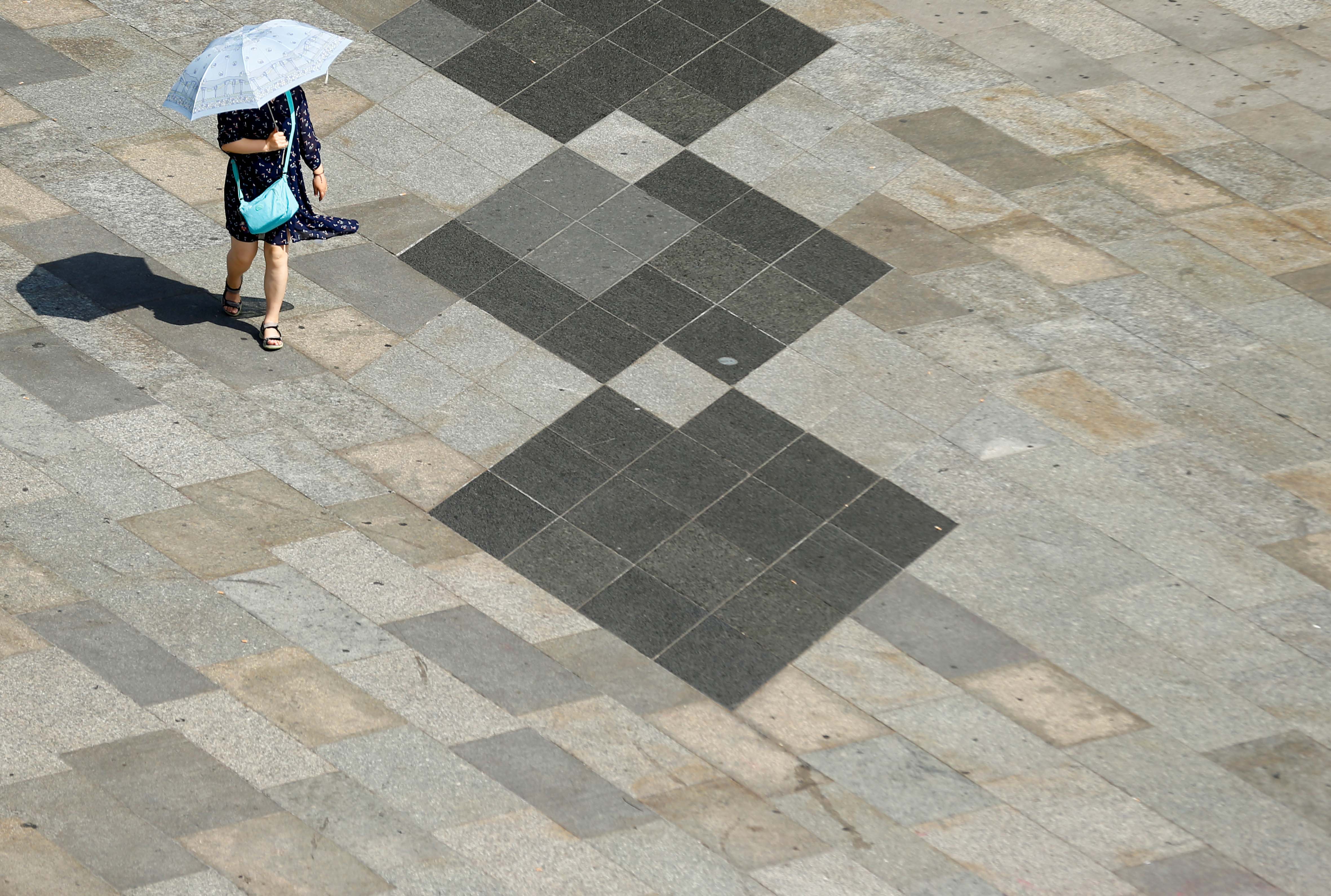 A woman shields herself from the sun with an umbrella on a hot summer day in Cologne, Germany, July 25, 2019. 