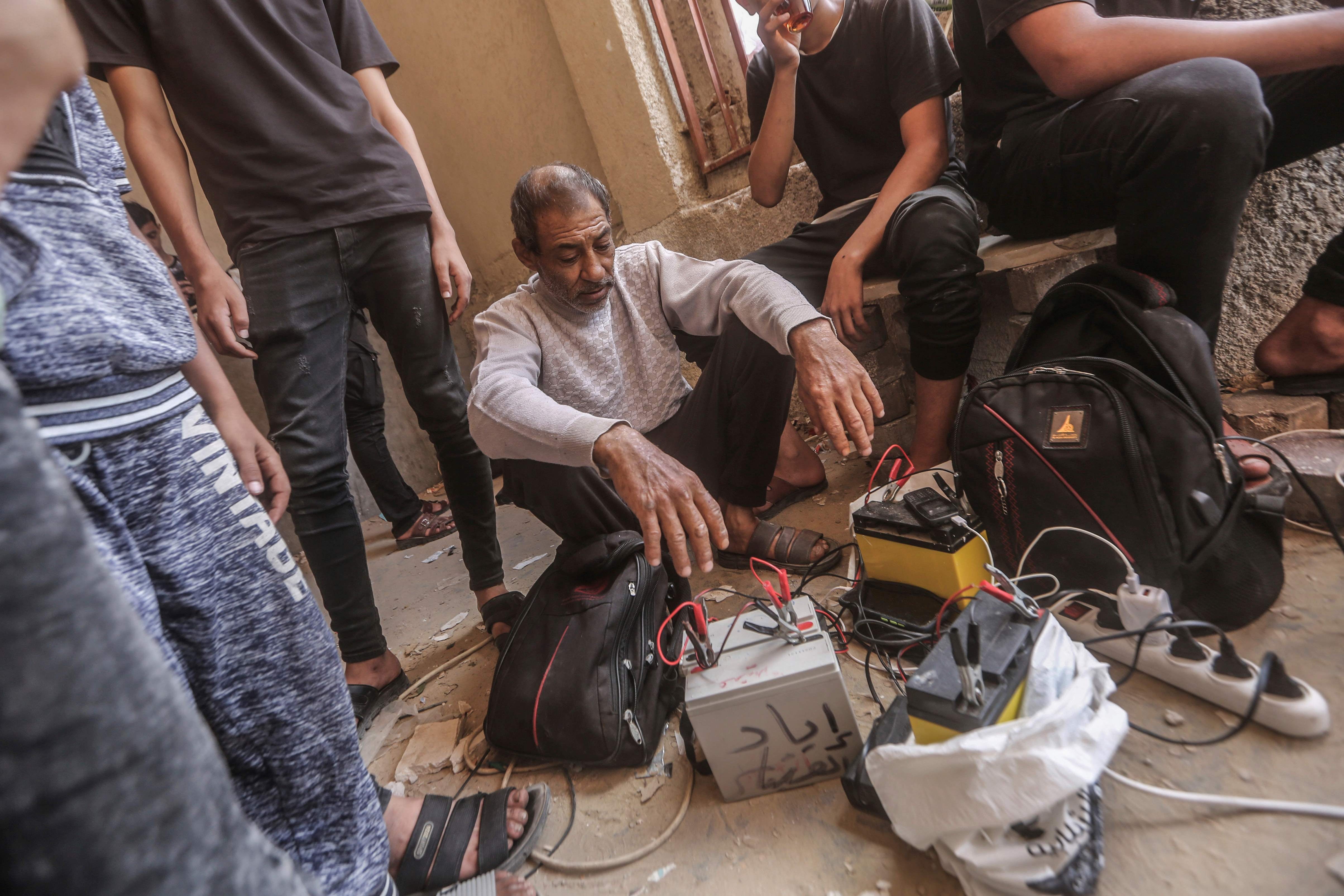 Palestinians in Khan Yunis, Gaza, use car batteries to charge their mobile phones, October 23, 2023.