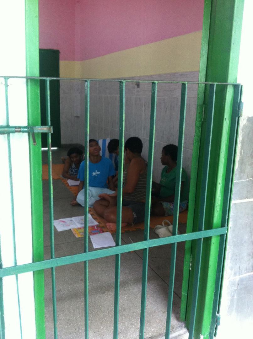 A group of children with physical and sensory disabilities drawing while sitting on the floor in a common room an institution in Rio de Janeiro. 