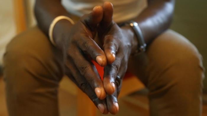 Clasped hands of interviewee are in focus in the foreground of the image