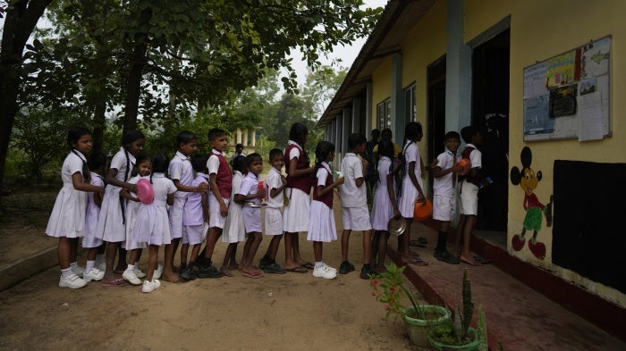 Children in school uniforms line up to receive food