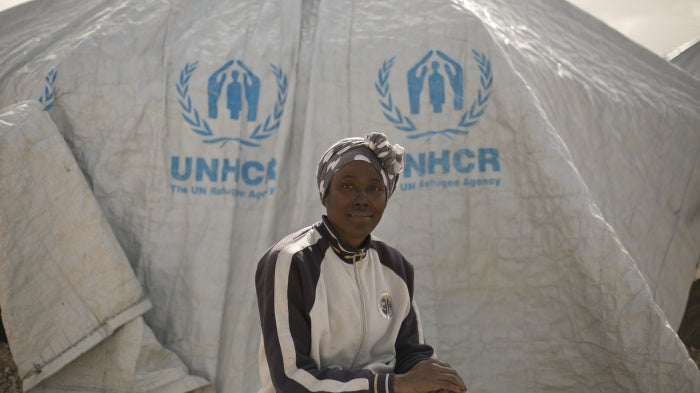 A woman poses for a portrait in front of a UNHCR tent