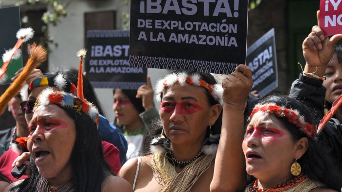 Indigenous women hold up placards in Spanish at a protest