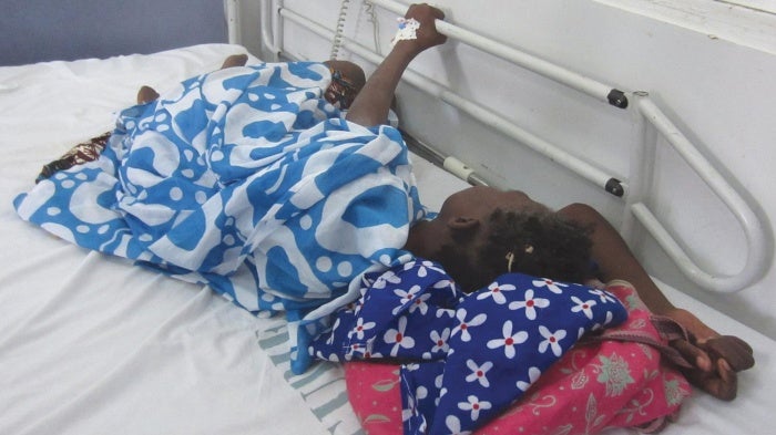 During a morphine shortage, a cancer patient in Dakar clutches onto the railing of her hospital bed because she is in pain and the medication she needs is unavailable.