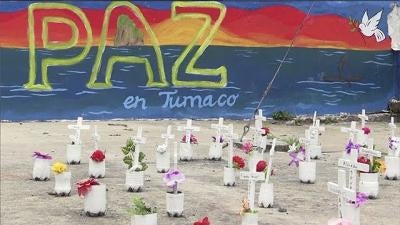 Mural that reads 'Paz en Tumaco' with graves/memorials in the foreground