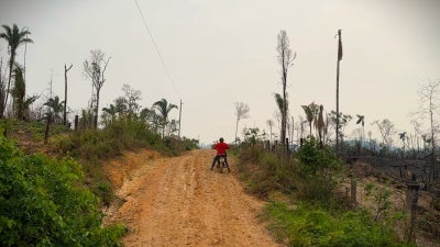 A man rides a motorcycle down a dirt road