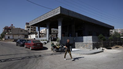 A person walks past the Al-Radwan guest house, where a deadly shooting occurred, in the predominantly Druze city of Sweida, Syria, July 25, 2025. 