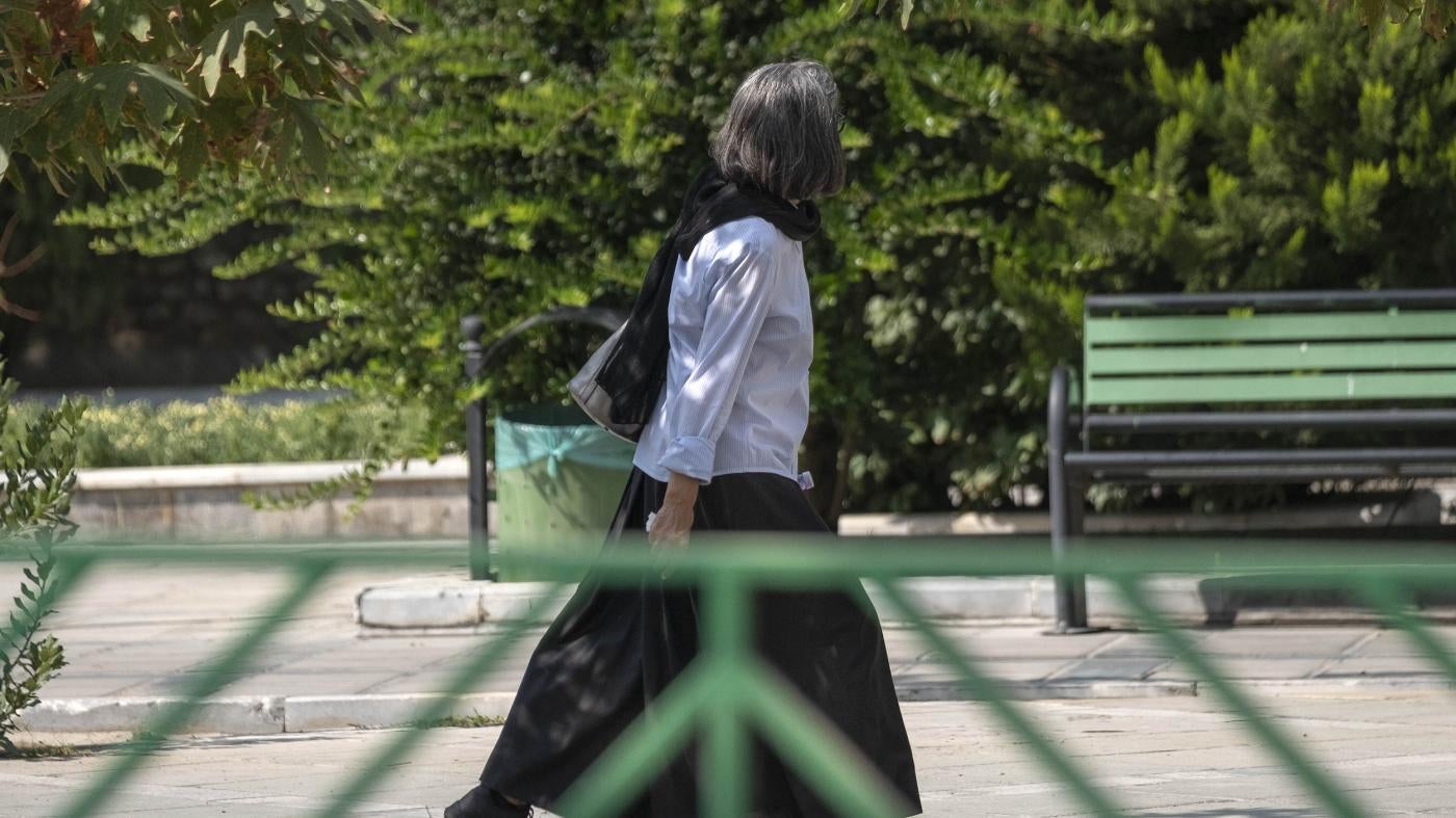 An Iranian woman walks along a street-side in Tehran without wearing her headscarf.