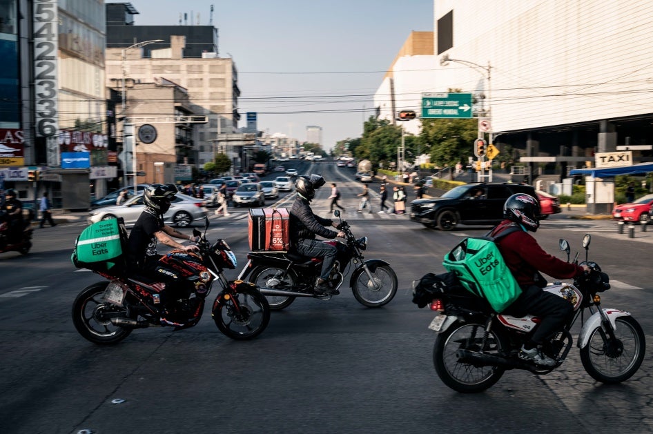 Delivery workers carry Uber Eats and Didi bags in Mexico City, Mexico, on December 12, 2024. 