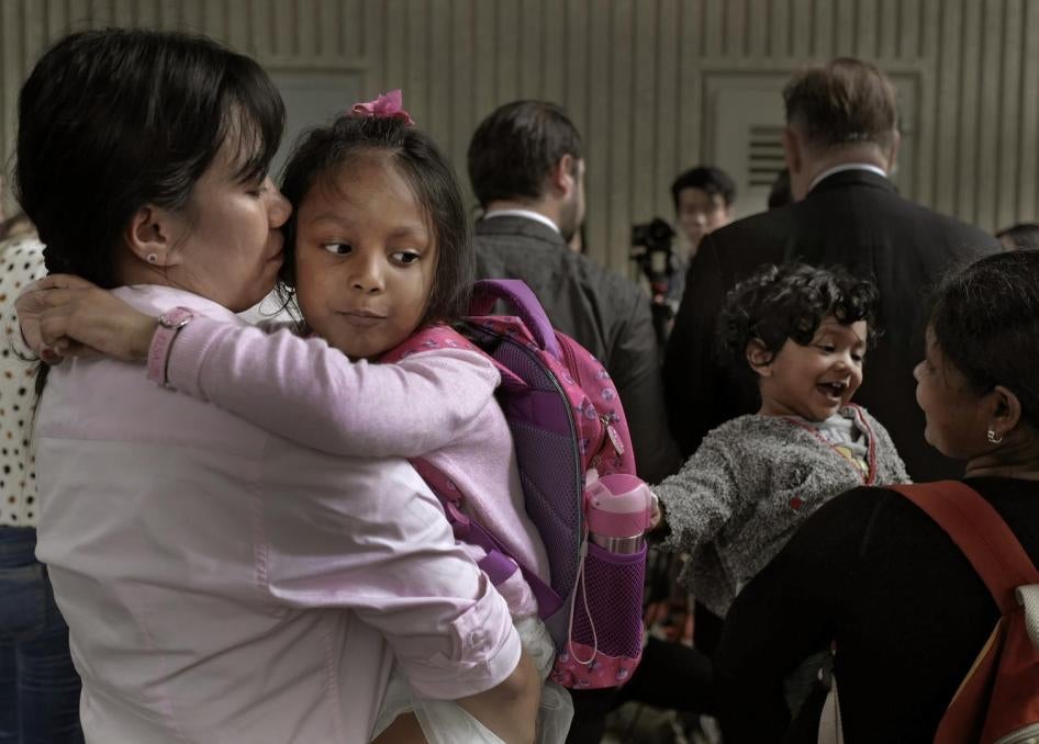 Two mothers hold their children in their arms as they wait outside the immigration department's building in Hong Kong, China.