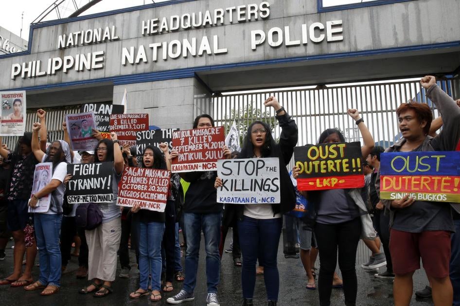 Veiled protesters, mostly relatives of victims of alleged extra-judicial killings, display placards during a protest outside the Philippine military and police camps