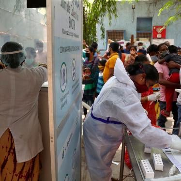 People wait to get tested for Covid-19 in Hyderabad, India. A crowd stands before two health care workers. 