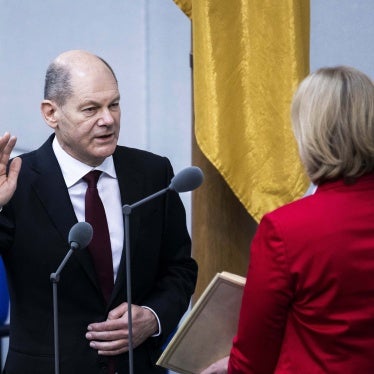 A man wearing a suit raises his right hand