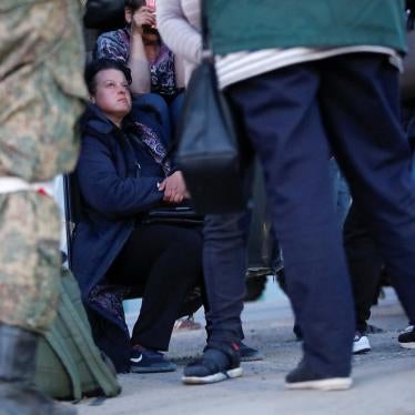 A soldier stands in front of civilians 