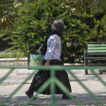 An Iranian woman walks along a street-side in Tehran without wearing her headscarf.