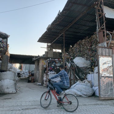A boy sits on a bicycle in front of a plastic recycling facility in Adana, Turkey.