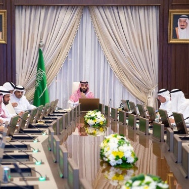 A man sits at the head of a large table during an official meeting,