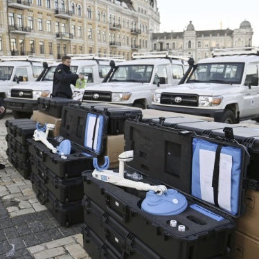 Two men stand by metal detectors used for demining.  
