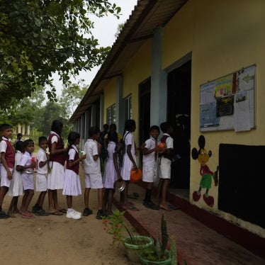 Children in school uniforms line up to receive food