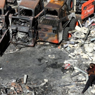 A woman walks in front of charred agricultural equipment, at the site of an Israeli strike in the southern Lebanese village of Msayleh, on October 11, 2025. 