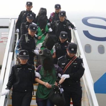 Police escort a group of people deported from Kenya as they get off a plane at Beijing Capital International Airport on April 13, 2016.