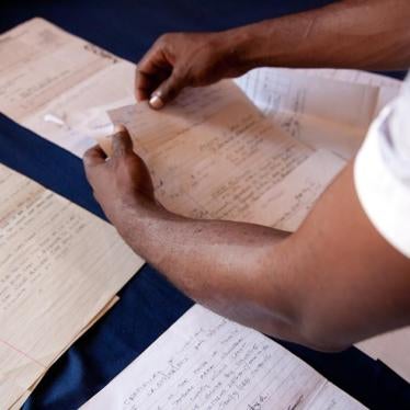 "Adam," arrested in Kenya in February 2015 on homosexuality charges and subjected to a forced anal exam, sorts through police documents on his case. © 2015 Zoe Flood