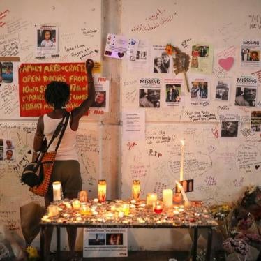 A woman writes on a wall covered with tributes to and pictures of the victims of the Grenfell apartment tower fire in North Kensington, London, Britain, June 18, 2017.
