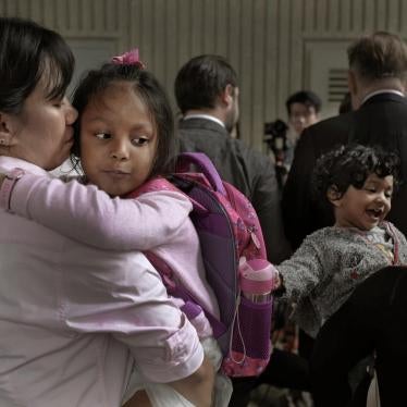 Two mothers hold their children in their arms as they wait outside the immigration department's building in Hong Kong, China.