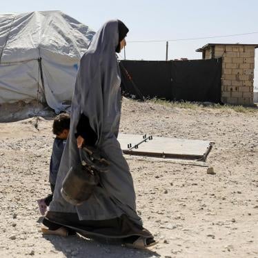 A woman walks with a child in Roj camp, which holds foreign wives and children of Islamic State (ISIS) members, in northeast Syria, September 2018. © 2018 Delil Souleiman/AFP/Getty Images