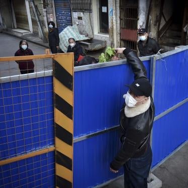 A man wearing a protective face mask passes groceries through the barricades blocked a residential area in Wuhan in central China's Hubei province, February 23, 2020. 